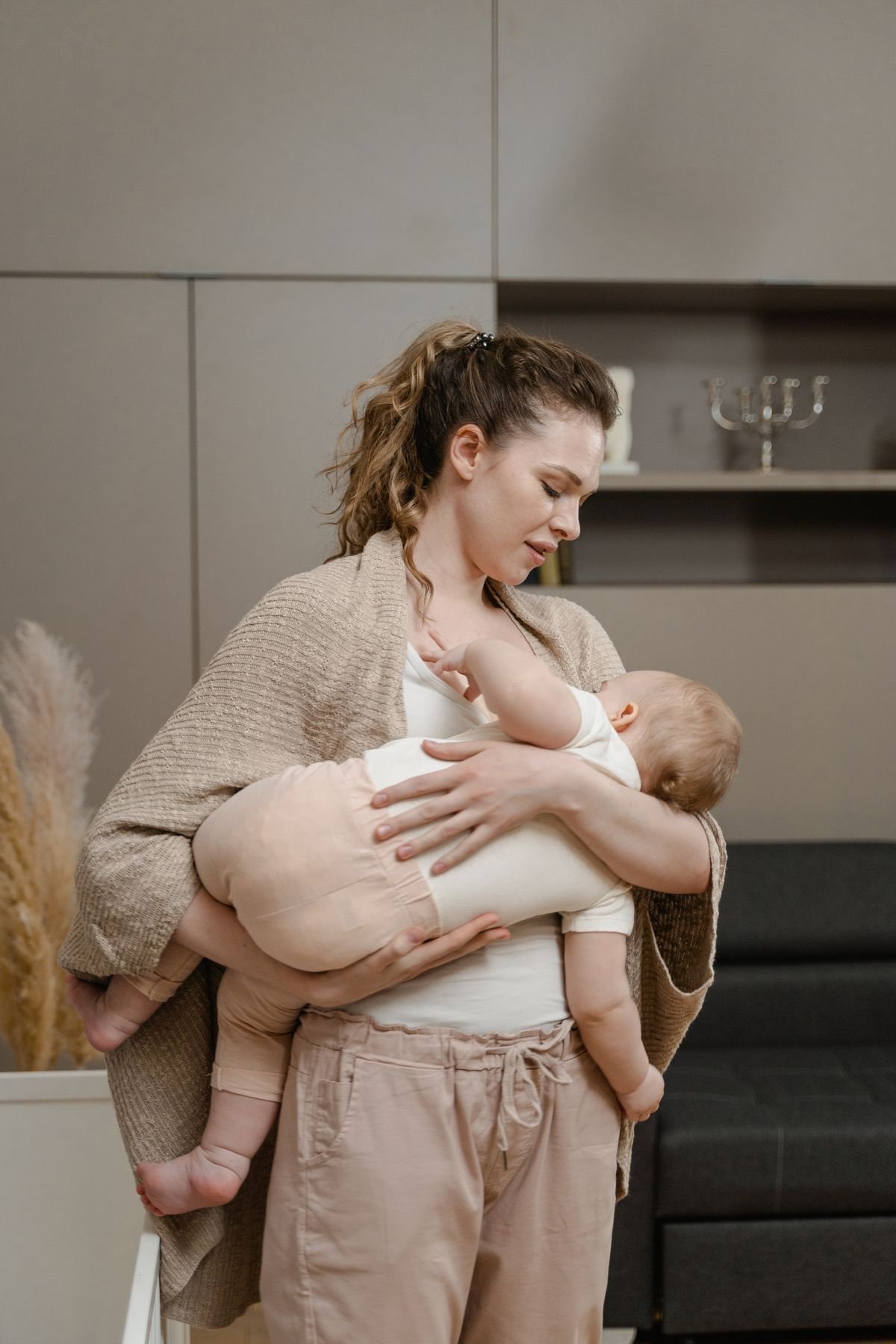 Mãe amamentando o bebê no sofá, ambiente aconchegante